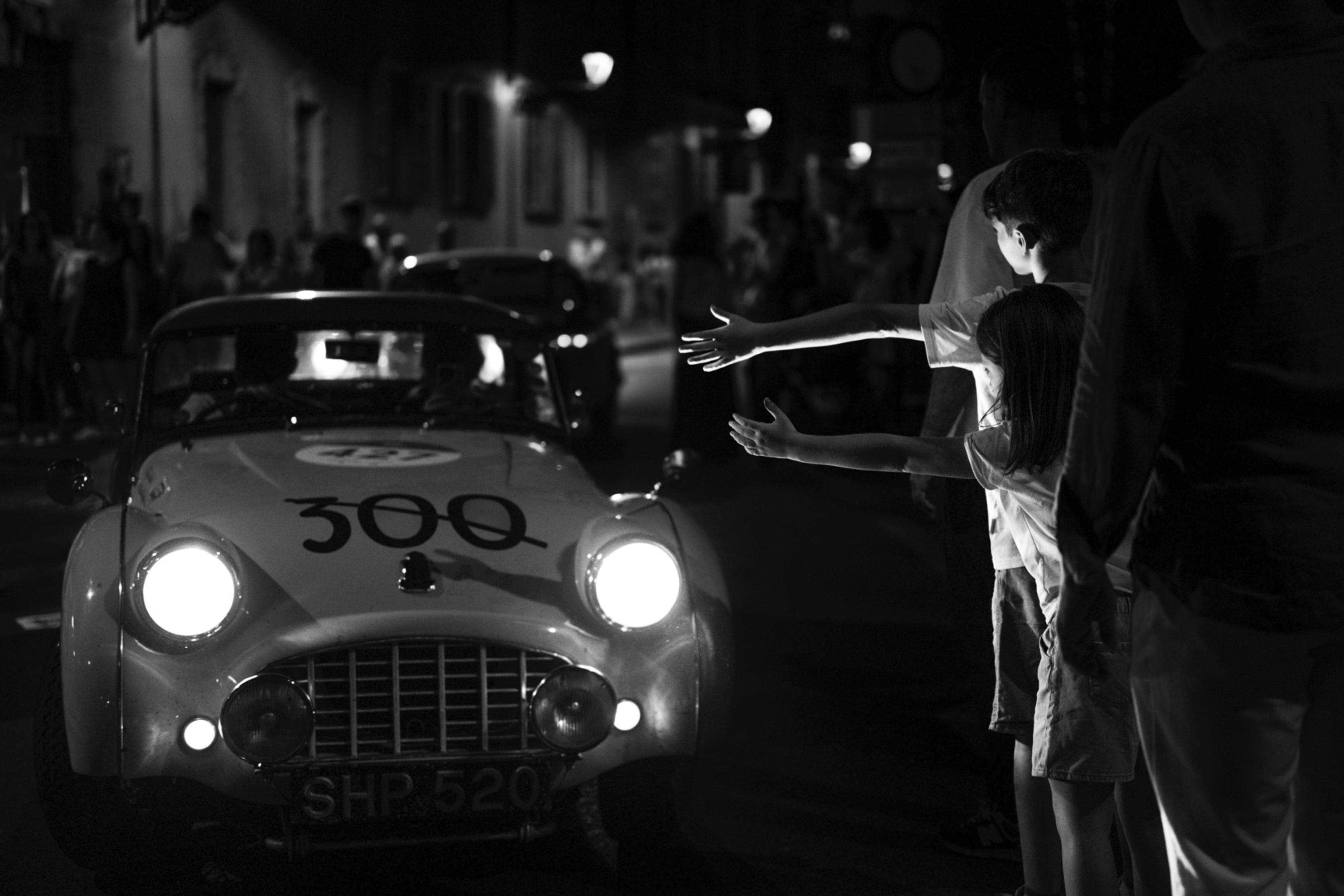 Children waving to a historic car in Parma during Mille Miglia, photograph by Simone Slawitz